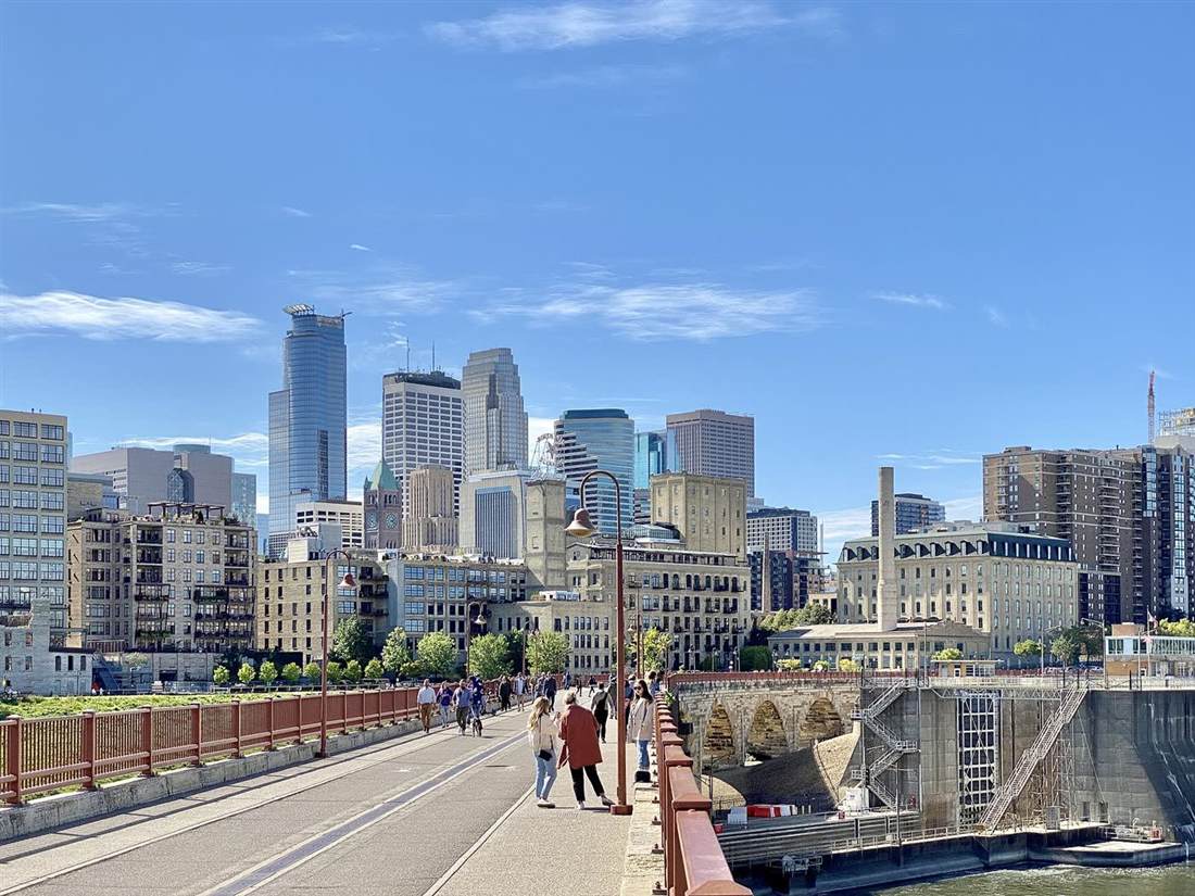 People crossing Stone Arch Bridge toward the Minneapolis skyline